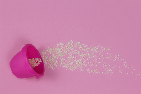Bright pink baking cup lying sideways on the pink background sprinkled with sesame.の写真素材