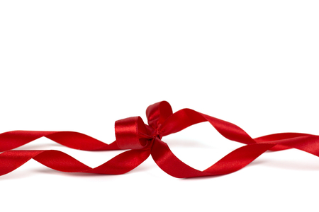 Beautiful decorative shiny red silk ribbon with a bow on isolated white background.の写真素材