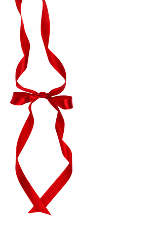 Beautiful decorative shiny red silk ribbon with a bow on isolated white background. Cut out. Copy space.の写真素材