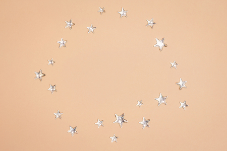 Beautiful shining silver stars with embossed transparent top arranged in circle on pastel yellow background. Copy space. Top view.の写真素材