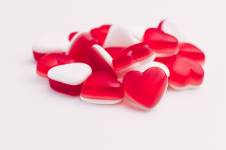 Pile of heart shaped red and white jelly sweets on white background for Valentine's Day celebration. Place for text.の写真素材
