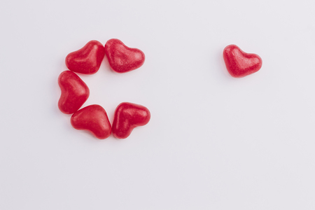 Concept of a lonely heart made of heart shaped red jelly sweets on white background. Valentines Day. Top view. Copy space.の写真素材
