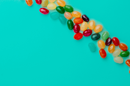 Top view of colorful bean sweet candies on bright turquoise blue background. Easter concep. Copy space.の写真素材