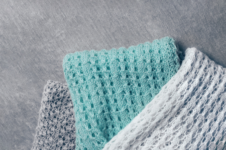 Stylish knitted taupe, white and mint colored sweaters in different knitting patterns piled on velvety fabric. Top view, copy space.の写真素材