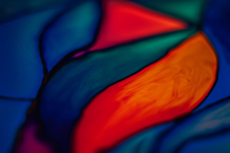 Blurred fragment of a beautiful colorful stained glass background including orange, yellow, blue, and violet pieces.の写真素材