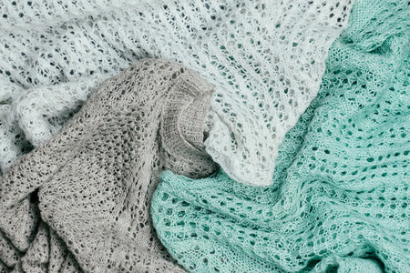 Piled stylish knitted pastel colored sweaters in different knitting patterns. Winter and spring...