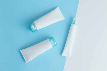 Three blue and white cosmetic tube mockups on light blue and white background. Copy space. Flat lay.の写真素材