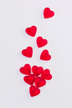 Concept of falling hearts made of heart shaped red jelly sweets on isolated white background. Top view. Copy space.の写真素材