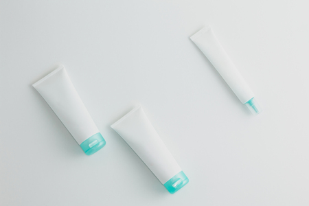 Three turquoise and white cosmetic tube mockups on white background. Copy space. Flat lay.の写真素材