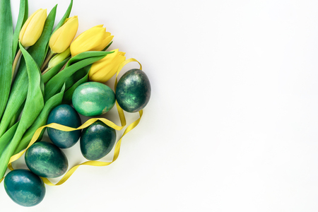 Beautiful spring concept with Easter eggs and yellow tulips on isolated white background. Flat lay. Copy space.の写真素材