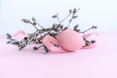 Palm sunday decoration of pussy willow with pink colored Easter egg and silk ribbon on light pink background. Close-up.の写真素材