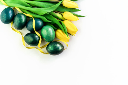 Beautiful spring concept with Easter eggs and yellow tulips on isolated white background. Copy space.の写真素材