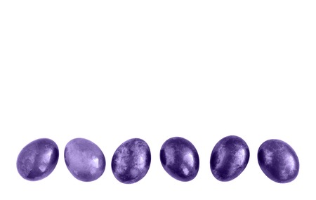 Ultraviolet Easter eggs in a row on isolated white background. Flat lay. Copy space.の写真素材