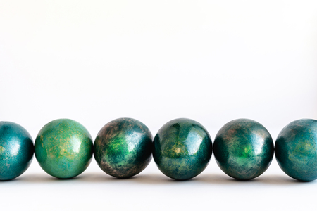 Easter eggs decorated in different shades of turquoise and gold lined on white background. Close-up. Copy space.の写真素材