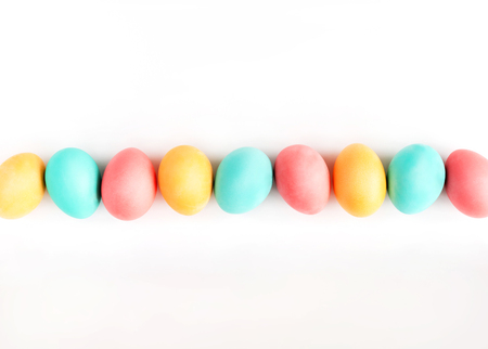 Colorful handmade Easter eggs lined on white background. Flat lay.の写真素材