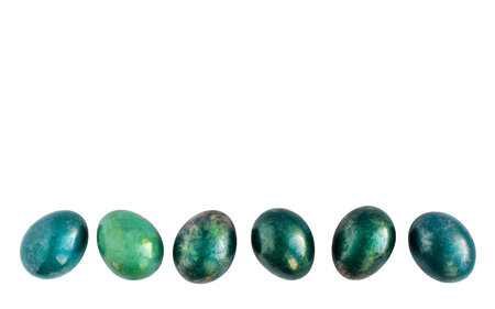 Easter eggs decorated in different shades of turquoise and gold in a row on isolated white background. Flat lay. Copy space.の写真素材