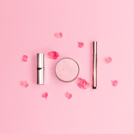 Flat lay composition with decorative makeup products and bright pink flowers on pastel pink background. Copy space.の写真素材