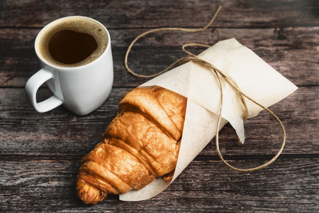 Perfect breakfast of croissant and coffee on wooden table. Rustic style. Close-up.の写真素材