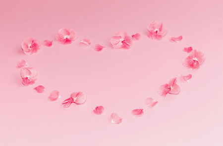 Composition of bright pink flowers in a shape of heart on pastel pink background. Copy space.の写真素材