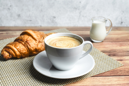 Perfect breakfast of croissant and coffee with milk on wooden table. Rustic style. Close-up.の写真素材