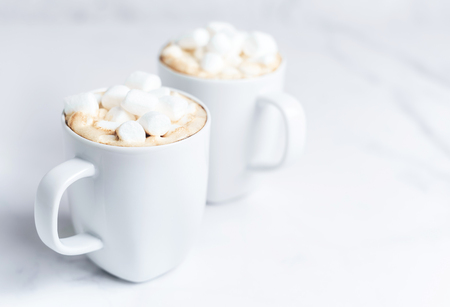 Romantic cozy desk top with two cups of coffee with marshmallows on marble table. Close-up. Space for text .の写真素材