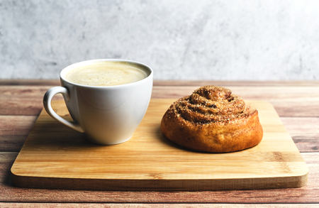 Perfect breakfast of homemade cinnamon bun and coffee on wooden table. Rustic style. Place for text.の写真素材