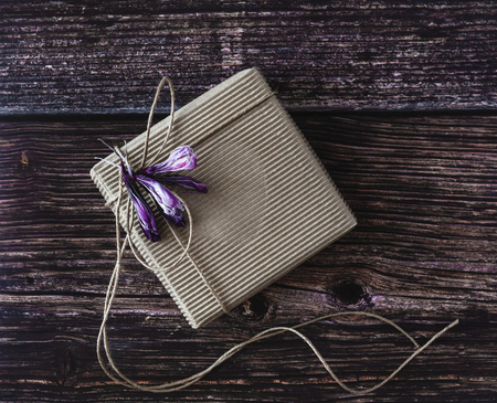 Handmade gift concept. Craft paper recycle gift box with flowers on wooden table. Rustic style. Top view.の写真素材