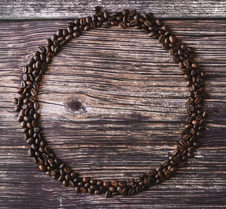 Frame made of spilled coffee beans on a wooden table. Rustic stile. Top view.の写真素材