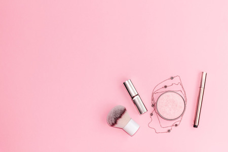 Flat lay composition with decorative makeup products and gold chain necklace on pastel pink background. Copy space.の写真素材