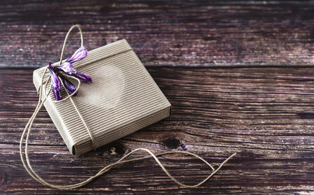 Handmade gift concept. Craft paper recycle gift box with flowers on wooden table. Rustic style. Close-up.の写真素材