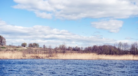Beautiful brightly lit spring landscape background. Blue river and trees on on a sunny day after melting snow.の写真素材
