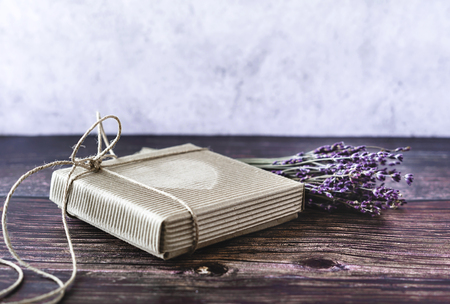 Handmade gift concept. Craft paper recycle gift box with lavender on wooden table. Rustic style. Close-up.の写真素材