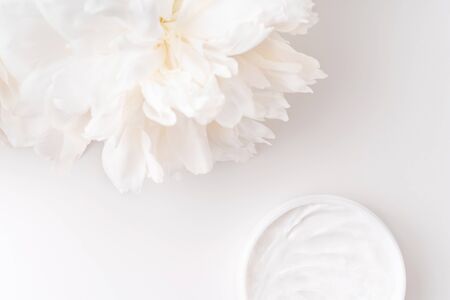 White peony and mockup face and body cream on white background. Cosmetics concept. Flat lay.の写真素材