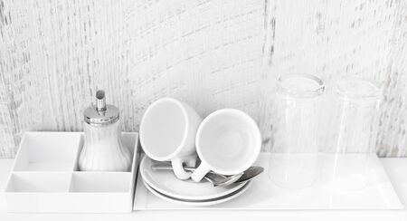 Coffee and tea making set of white cups, saucers, tea spoons and glasses on white porcelain tray. Hotel accomodation. Copy space.の写真素材