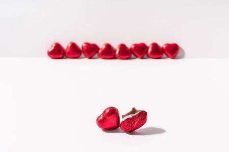 Heart shape chocolates wrapped in red foil on white background. Valentines day gift. Love and parting concept. Copy space.の写真素材