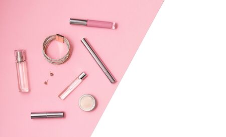 Flat lay composition with decorative makeup products and gold chain necklace on pastel pink background. Makeup and beaty concept. Copy space.の写真素材