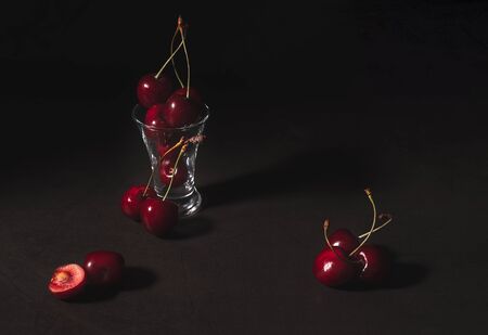 Still life of fresh delicious sweet cherry in a glass on dark background. Low key.の写真素材