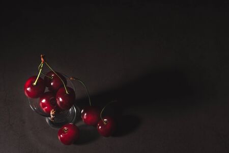 Still life of fresh delicious sweet cherry in a glass on dark background. Low key.の写真素材