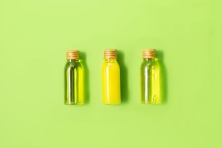 Flat lay of three small mockup bottles with spa cosmetic products on green background. Women beauty and beauty salon cosmetics concept. Eco concept.の写真素材