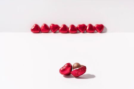 Heart shape chocolates wrapped in red foil on white background. Valentines day gift. Love and parting concept. Copy space.の写真素材