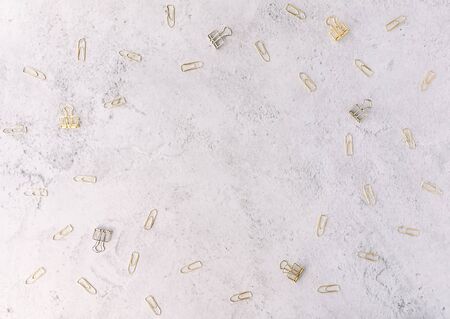 Set of silver and gold paper clips on light grey cement background. Flat lay. Office and business concept.の写真素材