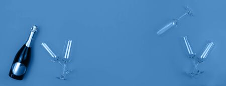 Champagne bottle and glasses on trendy blue background with place for text. Holiday concept. Flat lay style. Mockup for your web banner design.の写真素材