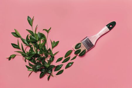 Colorful conceptual art background of paintbrush painting green leaves in shape of check mark on pink backdrop. Spring and summer concept. Flat lay style. Copy space.の写真素材