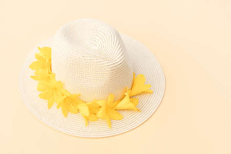 Straw hat with with yellow lily flowers on pastel background. Stylish retro design template. Yellow...