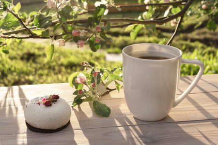 Beautiful porcelain coffee cup with mousse pastry dessert decorated with pink apple tree branches in...