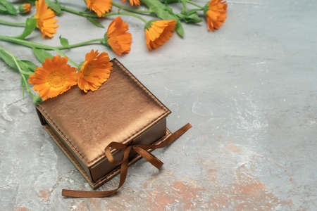 Beautiful vintage present box tied with silk ribbon decorated with marigold flower bouquet. Colorful background for celebration decoration design. Vintage wallpaper. Copy space.の写真素材