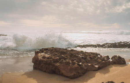View over sandy beach of Atlantic Ocean with waves crashing on the rock and make the splashing water...