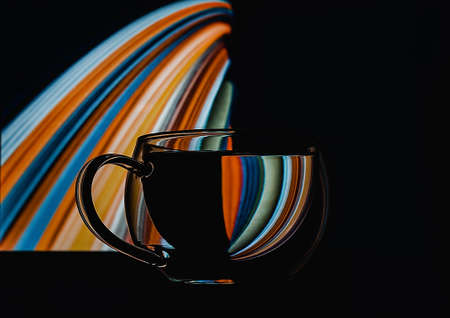 Abstract colorful refraction in transparent glass of water on isoleted black background for concept design. Optical illusion concept. Closeup. Copy space.の写真素材