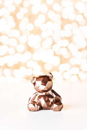 Gift card with chocolate bear on golden background of christmas lights bokeh. Mockup for decorative design. Christmas and New Year concept. Copy space.の写真素材