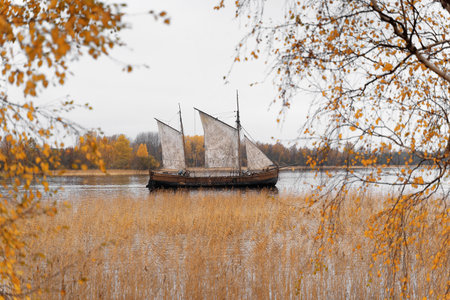 Wooden old ship in vintage style with all sails set in misty lake. Moody background.の写真素材
